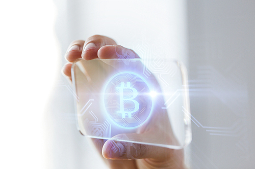 business, technology and cryptocurrency concept - close up of male hand holding and showing transparent smartphone with bitcoin on screen