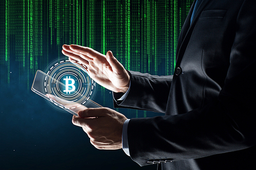 business, cryptocurrency and future technology concept - close up of businessman with transparent tablet pc computer and virtual bitcoin symbol hologram over binary code background