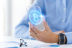 business, technology and cryptocurrency concept - close up of woman hand holding and showing transparent smartphone with bitcoin on screen