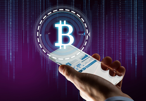 business, cryptocurrency and future technology concept - close up of businessman hand with charts on transparent smartphone and bitcoin hologram over binary code on ultra violet background