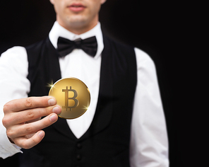 cryptocurrency, financial technology and business concept - close up of casino dealer holding bitcoin over black background