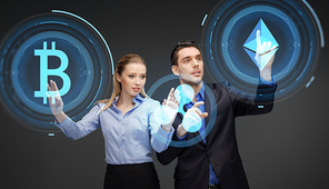 cryptocurrency, financial technology and business concept - businessman and businesswoman working with at virtual bitcoin, ethereum and holograms icons over dark background