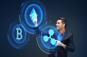 cryptocurrency, financial technology and business concept - smiling businessman working with virtual bitcoin, ethereum and ripple hologram over dark background