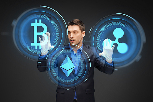 cryptocurrency, financial technology and business concept - businessman working with virtual bitcoin, ethereum and ripple hologram over dark background