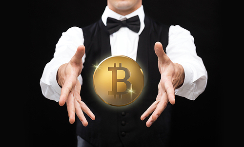 cryptocurrency, financial technology and business concept - close up of magician with bitcoin making trick over black background