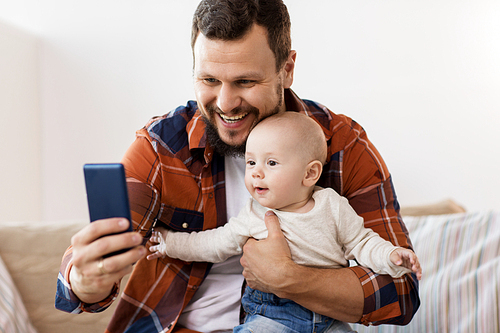 family, parenthood and people concept - happy father with little baby boy taking selfie at home