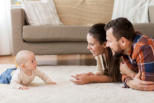 family, parenthood and people concept - happy mother and father playing with baby at home