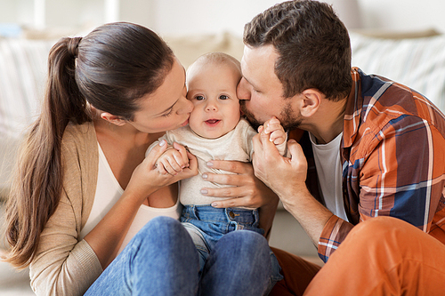 family, parenthood and people concept - happy mother and father kissing little baby at home