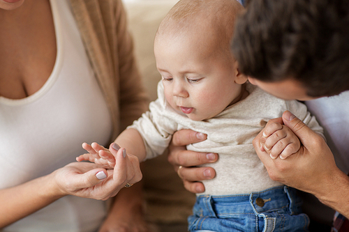 family, parenthood and people concept - close up of happy mother, father with baby at home