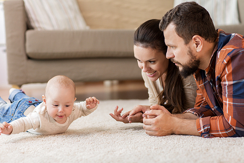 family, parenthood and people concept - happy mother and father playing with baby at home