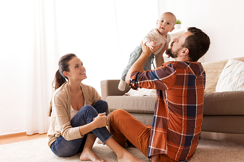 family, parenthood and people concept - happy mother and father playing with baby at home