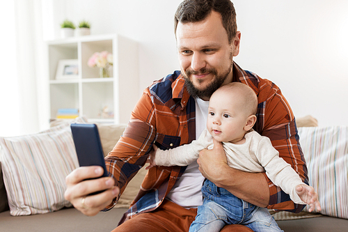 family, parenthood and people concept - happy father with little baby boy taking selfie at home