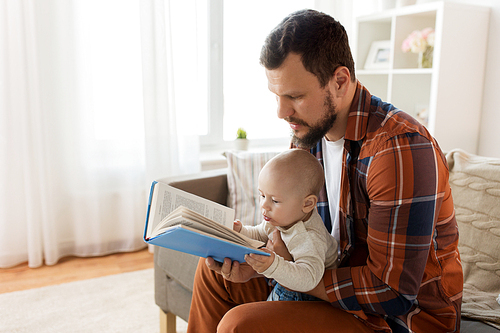 family, parenthood and people concept - happy father and little baby boy with book at home