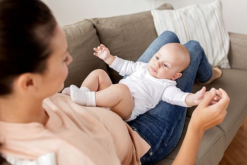 family, motherhood and people concept - happy mother with little baby boy lying on sofa at home