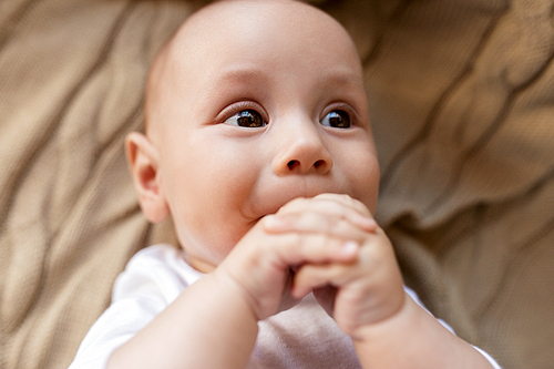 babyhood, childhood and people concept - close up of sweet little baby boy lying on blanket