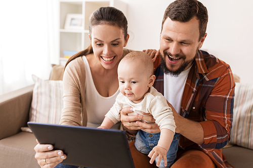 family, parenthood and people concept - happy mother and father showing tablet pc computer to baby at home