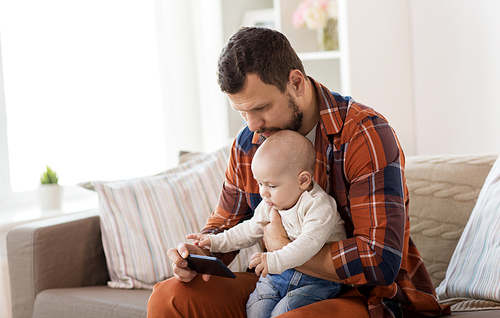 family, parenthood and people concept - happy father and little baby boy with smartphone boy at home