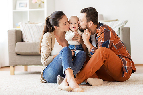 family, parenthood and people concept - happy mother and father kissing little baby at home