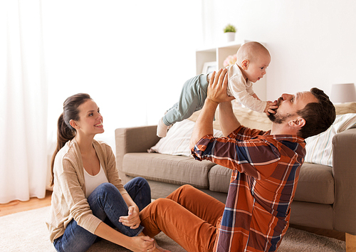 family, parenthood and people concept - happy mother and father playing with baby at home