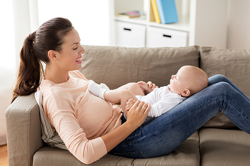 family, motherhood and people concept - happy mother with little baby boy lying on sofa at home