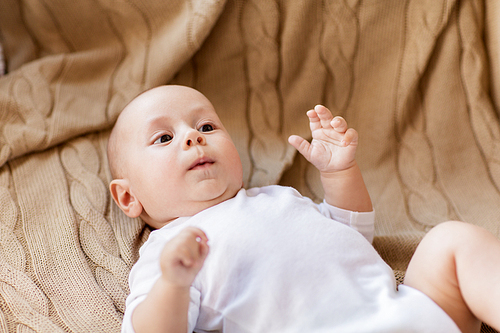 babyhood, childhood and people concept - sweet little baby boy lying on knitted blanket