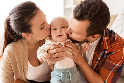 family, parenthood and people concept - happy mother and father kissing little baby at home