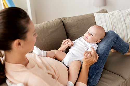 family, motherhood and people concept - happy mother with little baby boy lying on sofa at home