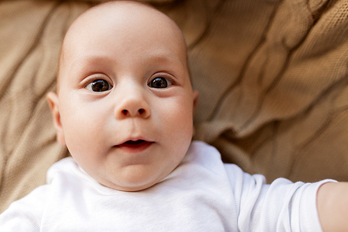 babyhood, childhood and people concept - close up of sweet little baby boy lying on blanket