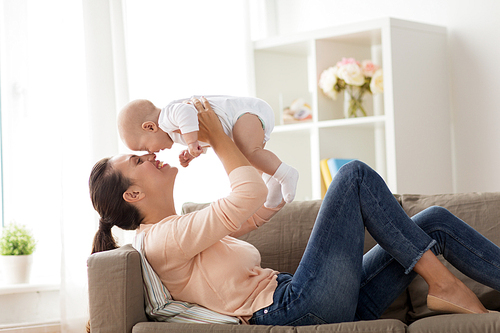 family, motherhood and people concept - happy mother with little baby boy lying on sofa at home