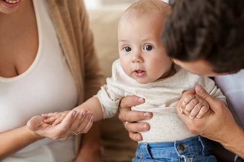 family, parenthood and people concept - close up of happy mother, father with baby at home