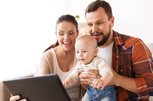 family, parenthood and people concept - happy mother and father showing tablet pc computer to baby at home
