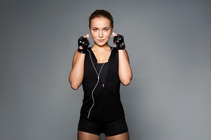 sport, fitness, technology and people concept - young woman with earphones listening to music in gym