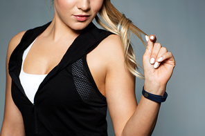 sport, technology and people concept - close up of young woman in black sportswear with fitness tracker posing in gym