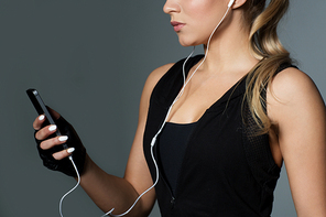 sport, fitness, technology and people concept - close up of young woman with smartphone and earphones listening to music in gym