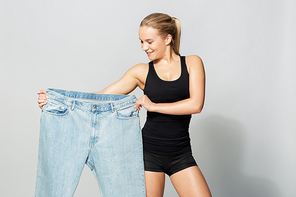 diet, weight loss and people concept - young slim sporty woman with oversize pants