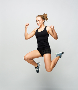 sport, fitness and people concept - young woman in black sportswear jumping in gym