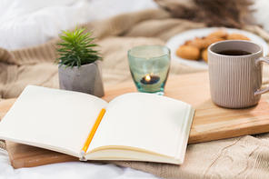 hygge and inspiration concept - diary, tea and candle in holder at home