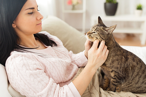 pets, hygge and people concept - close up of woman with tabby cat in bed at home