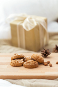 christmas, hygge, food and bakery concept - close up of homemade oatmeal cookies on wooden board ant gift box on background