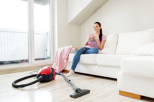 cleaning, household and people concept - happy woman or housewife with vacuum cleaner on floor drinking coffee at home
