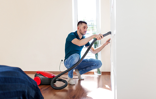 household, housework and cleaning concept - happy man with vacuum cleaner at home