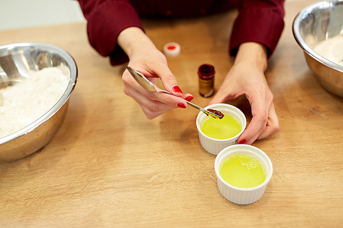 cooking, baking and people concept - chef hands adding food color into bowl with egg whites