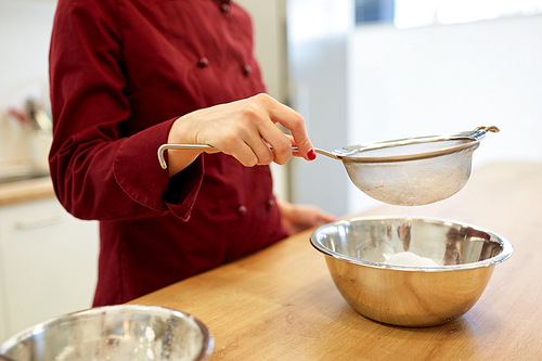 cooking food, baking and people concept - chef with strainer sieving flour into bowl and making batter or dough