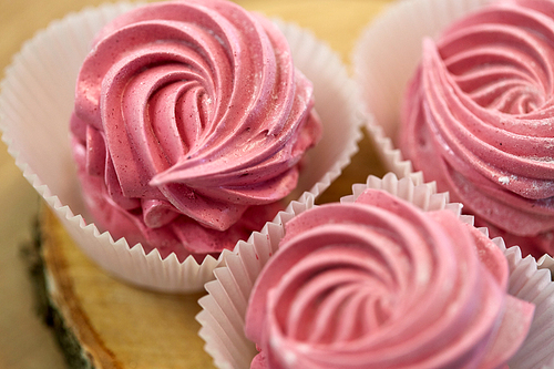 food, confection and sweets concept - close up of zephyr, marshmallow or whipped cream on wooden stand