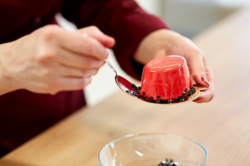 cooking, baking and confectionery concept - chef decorating mirror glaze cakes with chockolate sprinkles at pastry shop