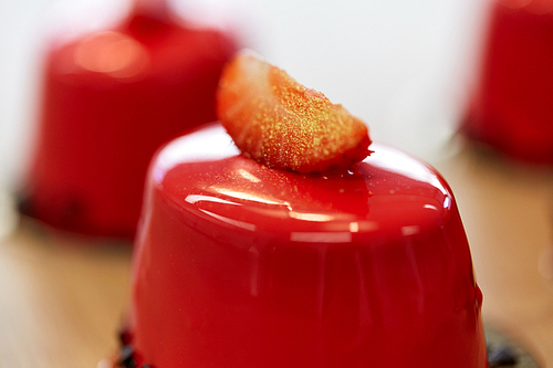 cooking, baking and food concept - close up of strawberry mirror glaze cakes with edible gold at confectionery