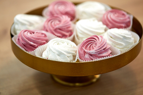 food, confection and sweets concept - zephyr, marshmallow or whipped cream on cake stand