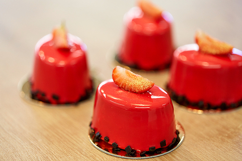 cooking, baking and food concept - strawberry mirror glaze cakes with edible gold at confectionery