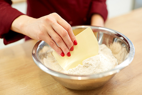 cooking food, baking and people concept - chef with spatula stirring flour in bowl and making batter or dough