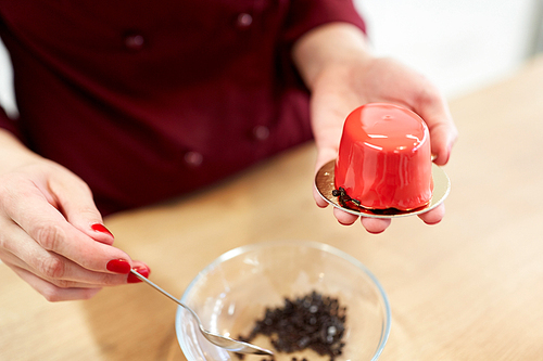 cooking, baking and confectionery concept - chef decorating mirror glaze cakes with chocolate sprinkles at pastry shop